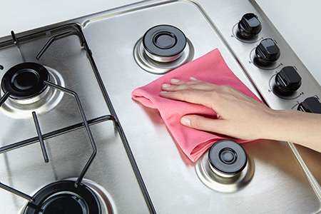 foto de uma pessoa limpando o fogão 