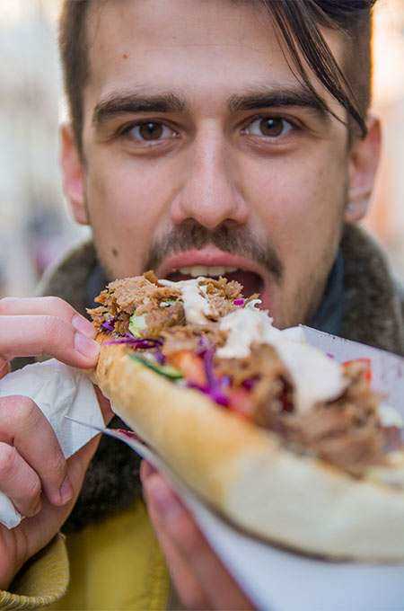 Foto de homem comendo um sanduiche