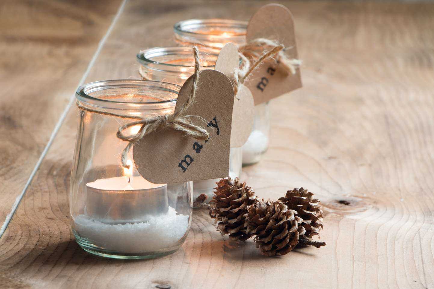 Foto de velas acesas dentro de vidros decorados para o natal